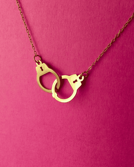 Colgante esposas dorado lucido en look casual moderno. Pieza de acero inoxidable con diseño audaz y vibrante.