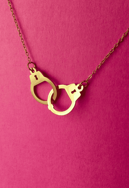 Colgante esposas dorado lucido en look casual moderno. Pieza de acero inoxidable con diseño audaz y vibrante.