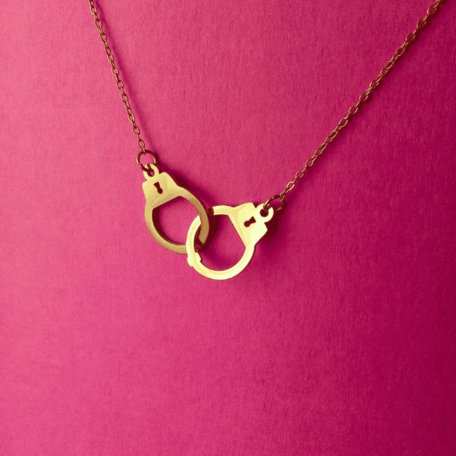 Colgante esposas dorado lucido en look casual moderno. Pieza de acero inoxidable con diseño audaz y vibrante.