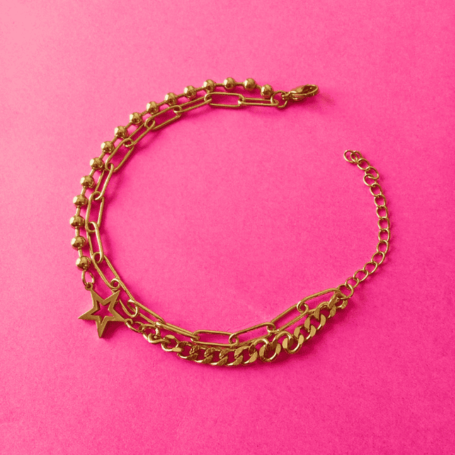 Pulsera dorada con estrella hueca central, diseño con eslabones y bolitas. Estilo atrevido en acero inoxidable.