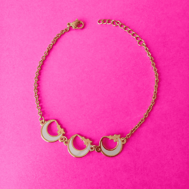 Pulsera dorada de acero inoxidable con tres colgantes de media luna blanca. Diseño bohemio y femenino.