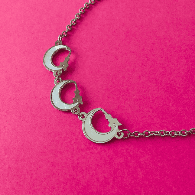 Tres medias lunas con borde plateado colgando de cadena de eslabones. Joya con aire bohemio.