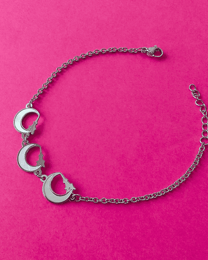 Pulsera plateada de acero inoxidable con tres colgantes de media luna blanca. Diseño místico y elegante.